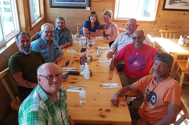 A group of people sitting at a table looking at the camera.